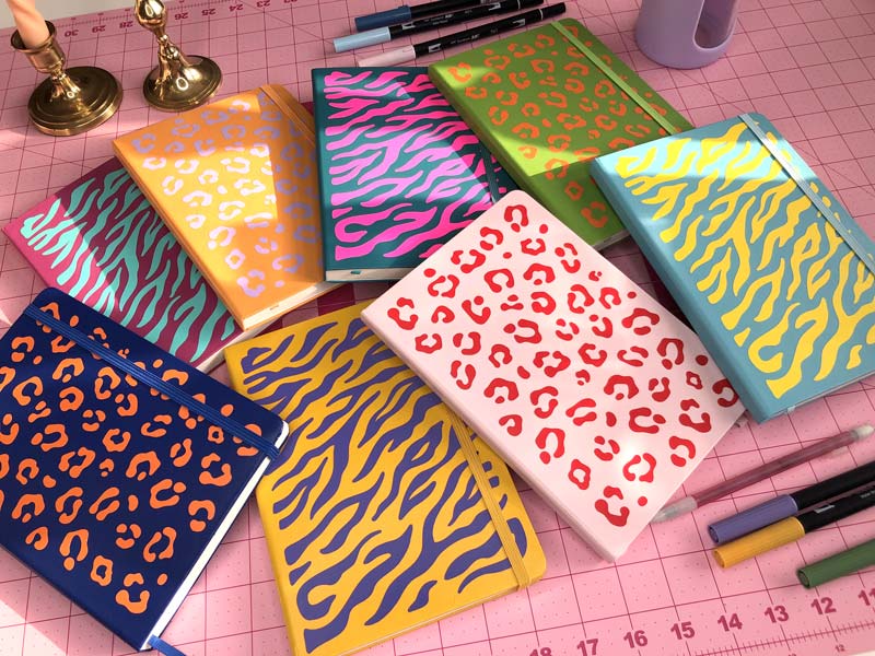 Colorful tiger stripe and leopard print journals scattered on a desk